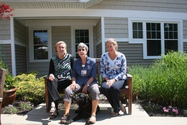 Therapy dog Sophie on the terrace outside Gosnell Memorial Hospice House with (from left) Stefanie Fairchild, Hospice of Southern Maine Volunteer Coordinator; Nan Butterfield, PawPrints volunteer and Sophie’s handler; and Kelli Pattie, Hospice Southern Maine Director of Volunteer Services.